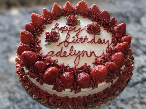 10-inch cake, vanilla frosting, fresh strawberry top border, red flower top, green leaf accents