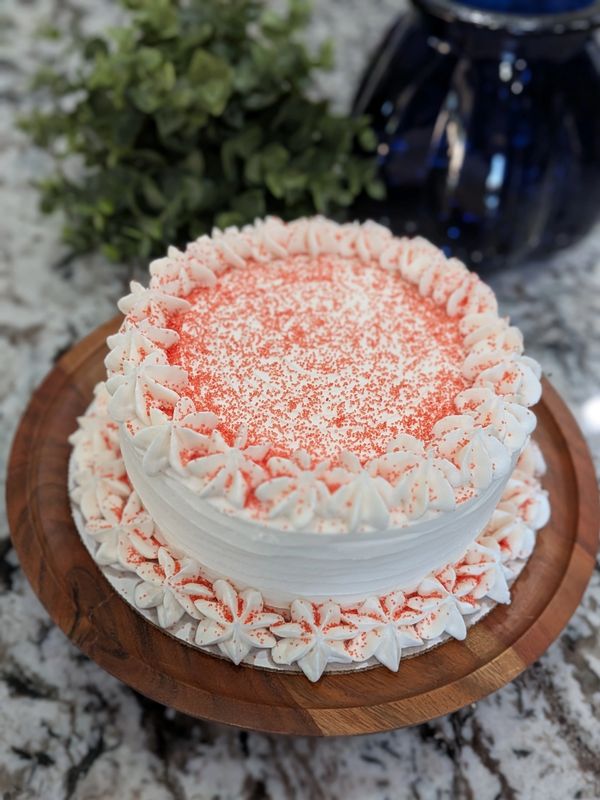 Our standard 6-inch red velvet in-stock cake: vanilla frosting, flower borders, red sprinkles