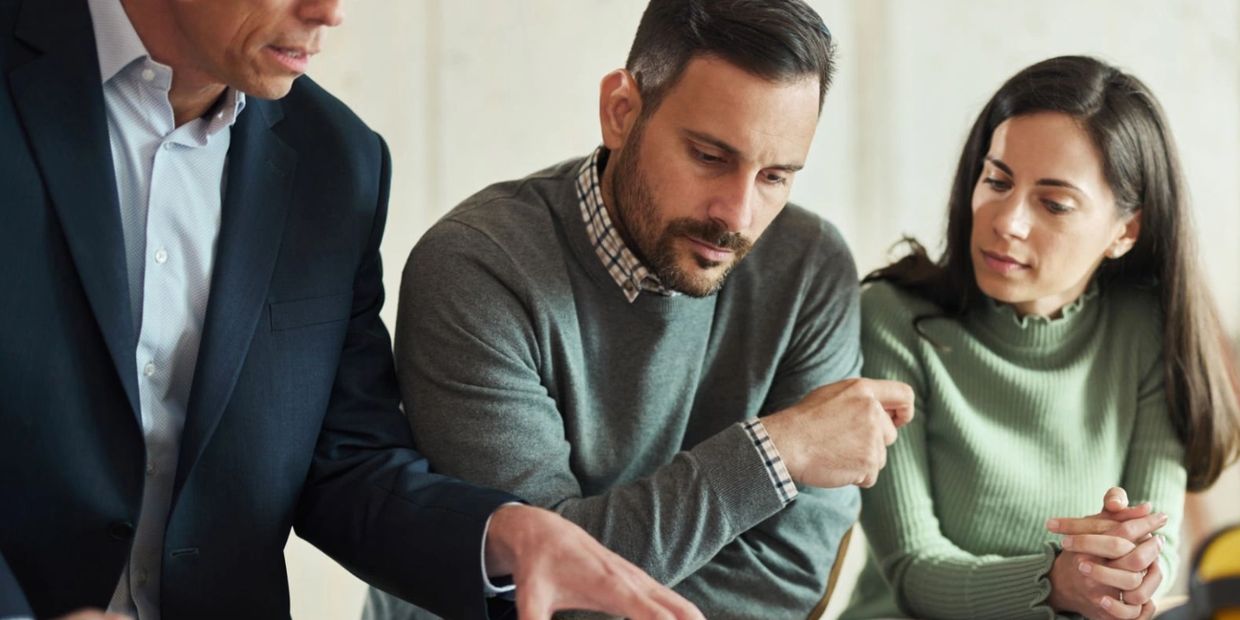 confident couple with home renovation consultant looking at blueprints