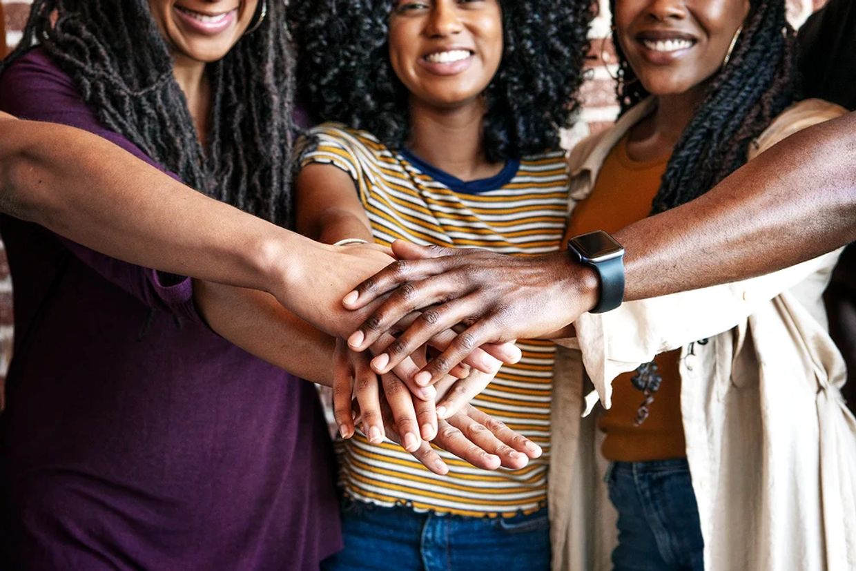 Women smiling piling hands on top of one another.