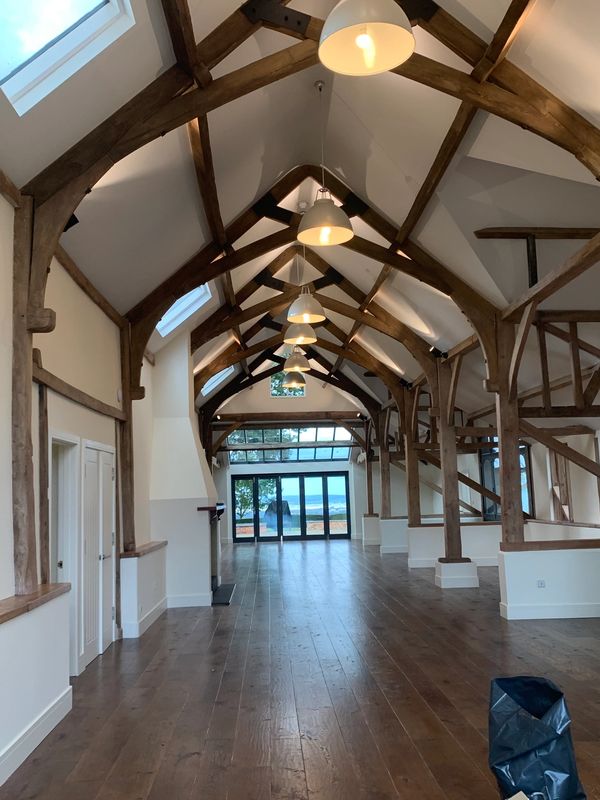 Spacious room with wooden beams and large windows overlooking the sea.