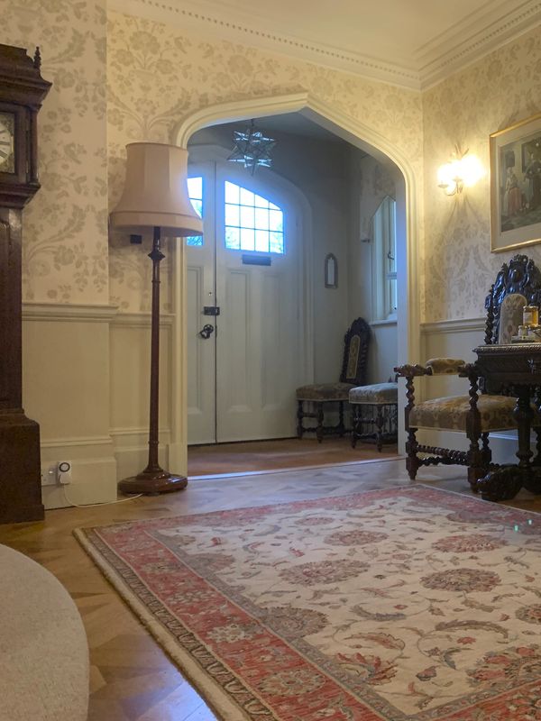 Cozy vintage living room with patterned wallpaper and traditional furniture.