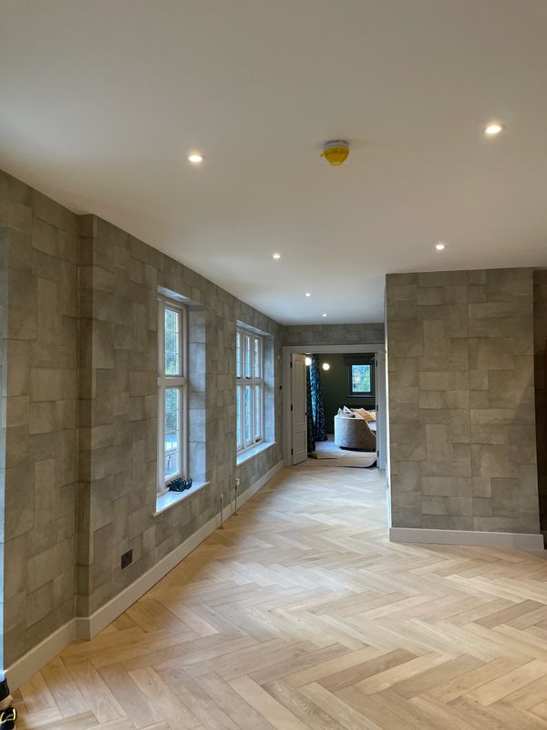Empty modern hallway with textured walls and wooden herringbone floor.