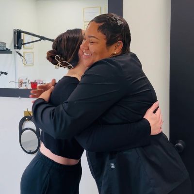 Two women warmly hugging each other, sharing a happy moment indoors.