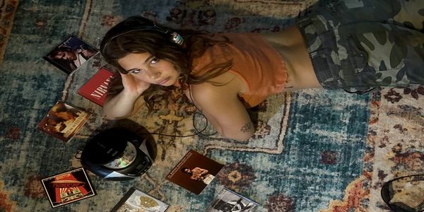 Young woman listening to music on headphones while lying on a rug.