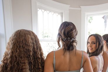 Bride smiling with bridesmaids in sage green dresses during wedding getting ready Naples, Florida.