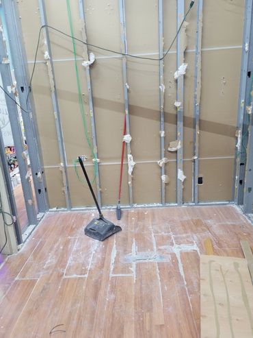 Construction site with exposed walls and cleaning tools on the floor.