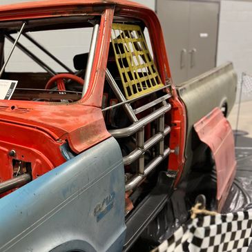 Close-up of a vintage race truck with roll cage and net window.
