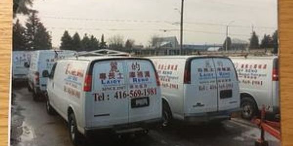 Two white laundry service vans parked side by side with company information on the back.