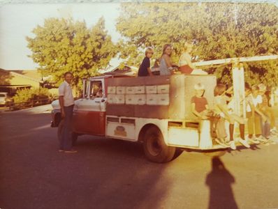 Group of people with a vintage truck in a sunny neighborhood.