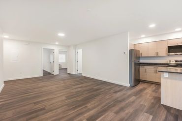 Modern open-concept apartment with wood flooring and a light wood kitchen.