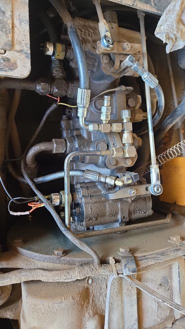 Close-up of a dusty mechanical component with hoses and metal fittings.