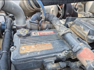 Close-up of a dusty engine compartment with warning labels and hoses.