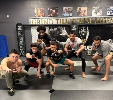 Six men in a martial arts gym posing in a crouched fighting stance.