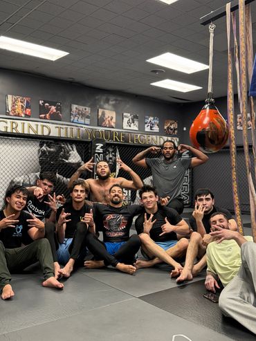A group of men posing in a gym with motivational quotes on the wall.