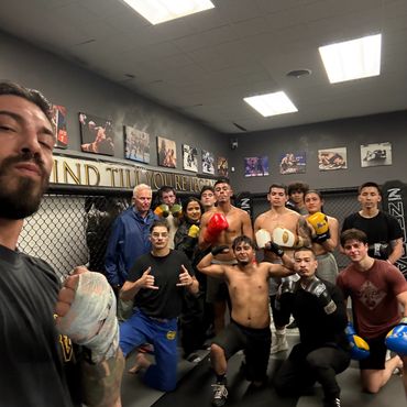 A group of diverse fighters posing inside a MMA training gym.