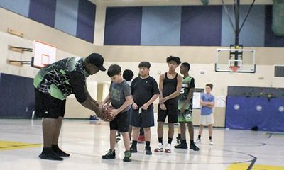 Coach teaching kids basketball skills in gym.
