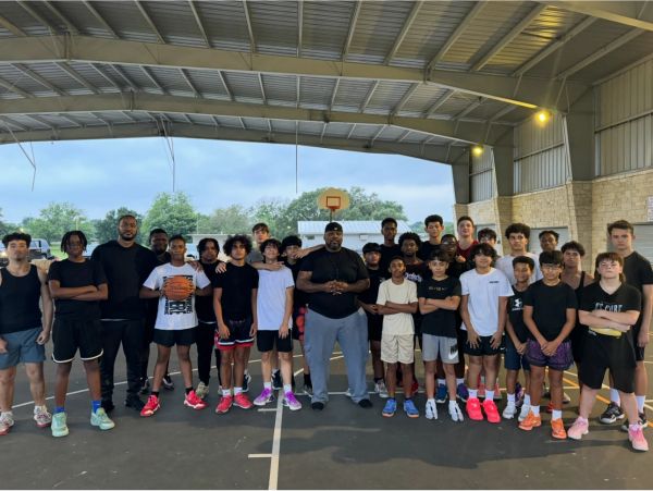 Group of young basketball players and coaches posing on court.