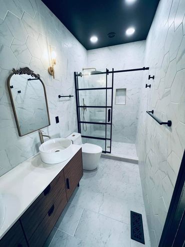 Modern bathroom with hexagonal tiles, black-framed shower, and elegant wooden vanity.