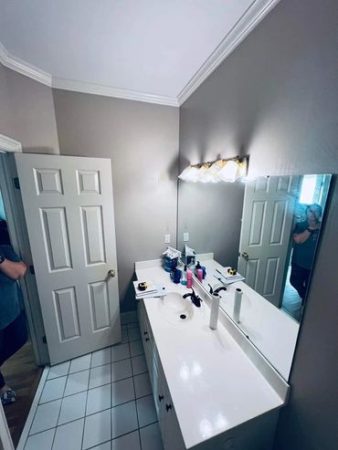 Bright bathroom with a large mirror and white counter.