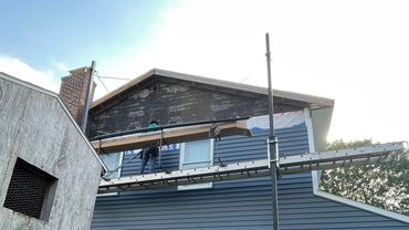 A person working on house siding installation on scaffolding.