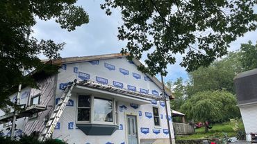 House under renovation with Lowe's branded wrap and ladders around.