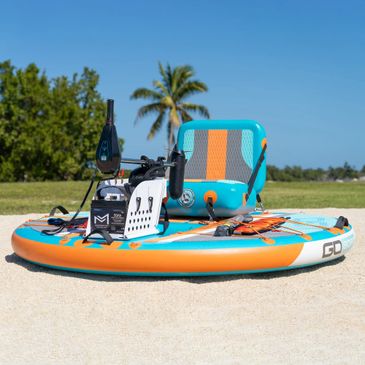 Colorful motorized paddleboard on sandy shore under clear blue sky.