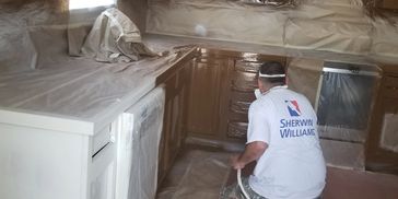 protective film in room with man painting cabinets