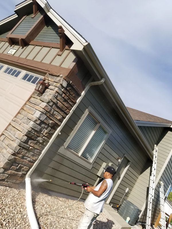 man cleaning home exterior for painting