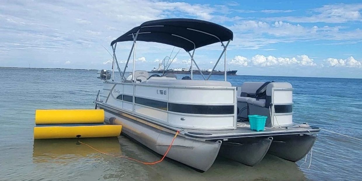 Bote pontón amarrado en el agua con dos flotadores amarillos.