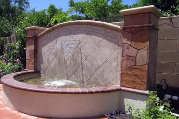 Stone, tile, and brick fountain adds waterfall sound to the outdoor living space in Orange County