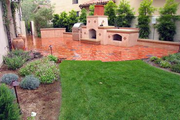 Custom hardscaping on outdoor fireplace, grill and Spanish style patio with landscaping in Orange Co