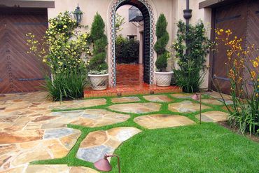 Large Mediterranean partial sun front yard with stone driveway and landscaping in Irvine