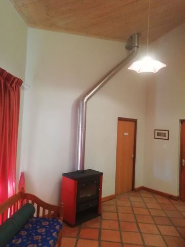 Cozy room with a red wood stove and wooden bench against white walls.