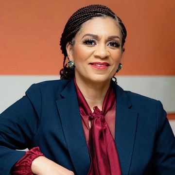 Confident woman smiling, dressed in a navy blazer and burgundy blouse.
