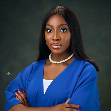 Confident woman in blue outfit with pearl necklace.