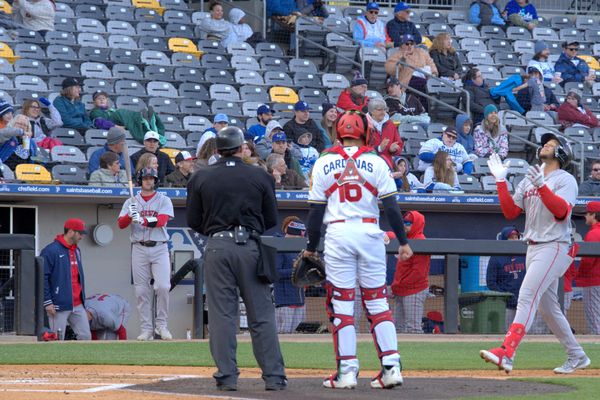 Baseball players and an umpire at home plate during a game with spectators in stands.