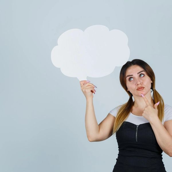 Woman holding a blank thought bubble while thinking.