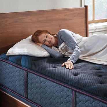 Woman resting on a bed with a comfortable mattress.