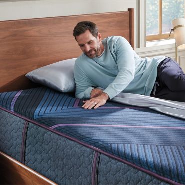 Man lying on a bed with a blue mattress.