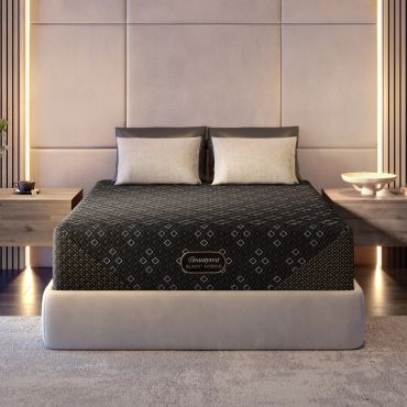 Modern bedroom with a stylish black mattress and beige cushioned headboard.