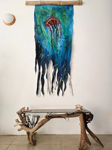 Artistic jellyfish tapestry above a rustic wooden table in a minimalist room.
