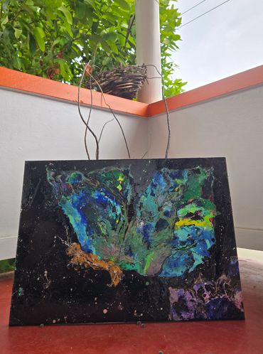 Abstract butterfly painting with vibrant colors on a black canvas.