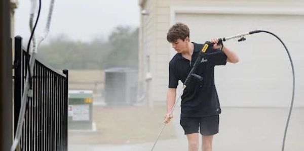 Young man pressure washing outdoors.