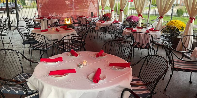 Outdoor dining area with tables set in white and red theme under a canopy.