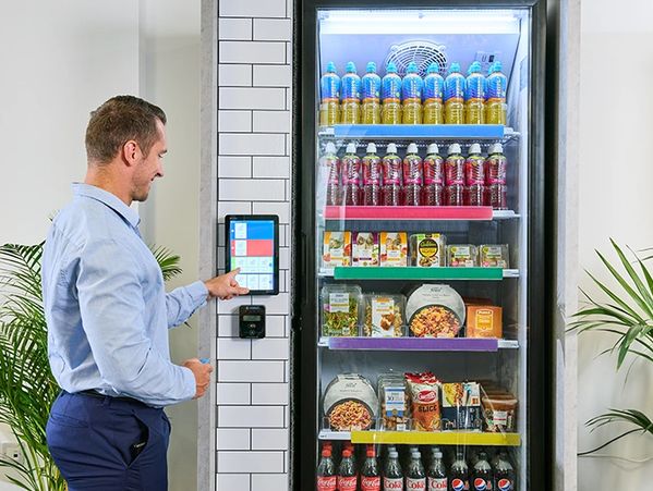 Man uses touchscreen to select items from a refrigerated vending machine.