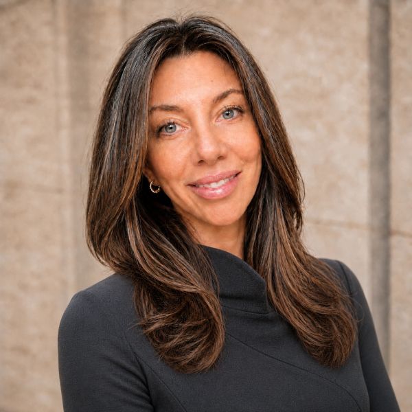 Smiling woman with long brown hair wearing a black top.