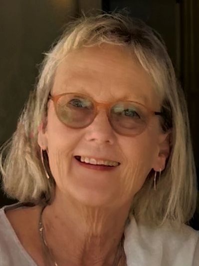 Smiling older woman with glasses and earrings.