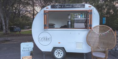 white Vintage caravan with timber trimmings  set up to serve coffee and french toasties at a private