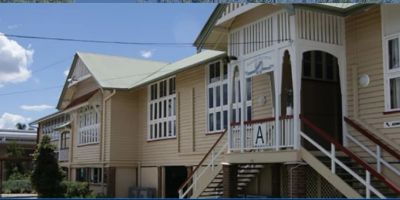 Row of beige wooden houses with stairs and decorative windows under a bright blue sky.